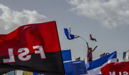 Un joven sostiene la bandera de Nicaragua y la del Frente Sandinista, durante un aniversario del triunfo de la revolución.