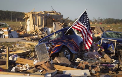 Carrocería de un coche con la bandera de Estados Unidos entre los escombros de un negocio en un barrio cerca de Vilonia, Arkansas.