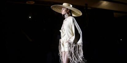 La colección de Roberto Verino para la próxima primavera toma como inspiración la estética mexicana: desde las culturas precolombinas hasta los flecos del atuendo tex-mex. En la imagen, la primera salida: un traje corto con flecos, botas de cowgirl y gran pamela de rafia.