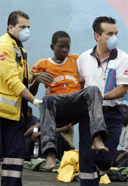 Uno de los inmigrantes llegados a Tenerife, transportado por dos miembros de los servicios sanitarios.
