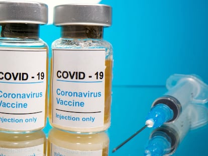 Viales, con la indicación 'COVID-19 / Vacuna del coronavirus / Sólo inyectable', y jeringa, ante un logo de la farmacéutica Pfizer.