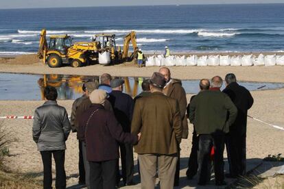 Varios vecinos mirando las obras en la playa de A Frouxeira