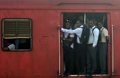 Viajeros en la puerta de un vagón de tren de Sri Lanka de camino al trabajo en Colombo.