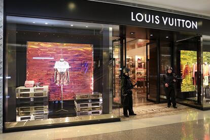 Security personnel stand guard with weapons outside a Louis Vuitton shop at a shopping mall in Shanghai 