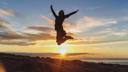 Una joven salta al aire durante la puesta de sol en una playa de Finisterre, en Galicia.