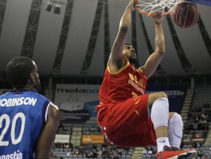 El brasileño de UCAM Murcia  machaca la canasta ante los jugadores del Gipuzkoa Basket, Jason Robinson, a la izquierda, y Doblas.