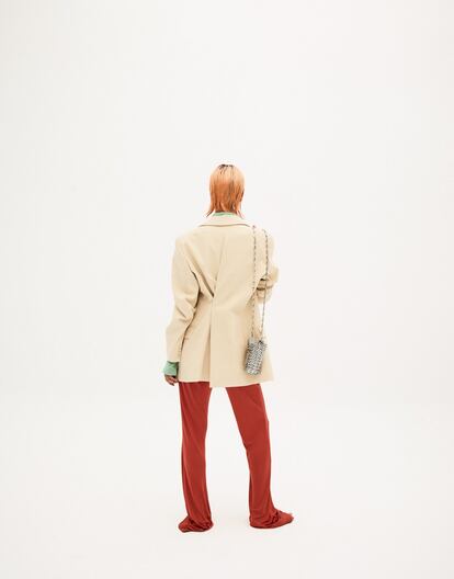 Americana con pinza trasera de Jacquemus para Mytheresa.com; camisa de licra y pantalón de punto de seda color caldero, ambos de Acne Studios, y bolso Mini 1969 color plata, de Paco Rabanne.
