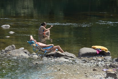 Dos personas se remojan en la orilla del río Miño, el martes en Orense. Los termómetros de la totalidad del territorio gallego alcanzaron valores “extremos” debido a la ola de calor que comenzó la semana pasada y que durará hasta el viernes 15 de julio.