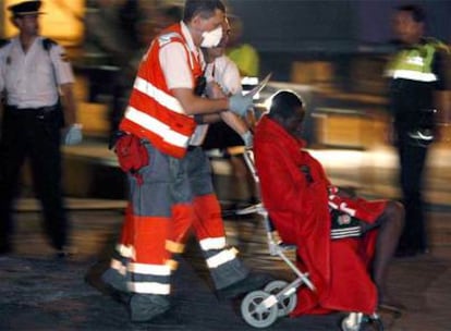 Uno de los inmigrantes es trasladado en camilla por miembros de la Cruz Roja a su llegada al puerto de Málaga.