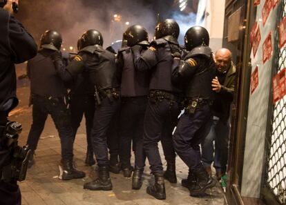 Un hombre intenta salir de la zona donde se están produciendo los enfrentamientos entre la policía y los manifestantes tras la marcha del 14-N