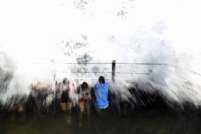 Unas personas desafían la fuerza de las olas en la playa de San Blas en La Libertad (El Salvador).