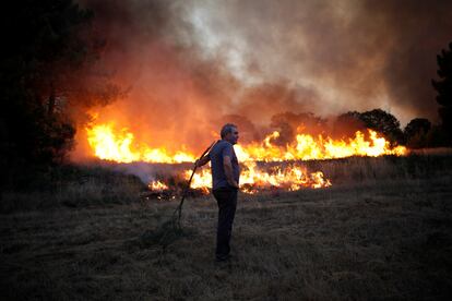 Un hombre mira como el fuego quema el pasto en Verín.