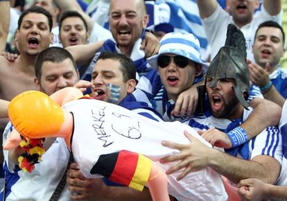 Seguidores griegos se pasan una muñeca hinchable que luce una camiseta con el dorsal de "Merkel 69".
