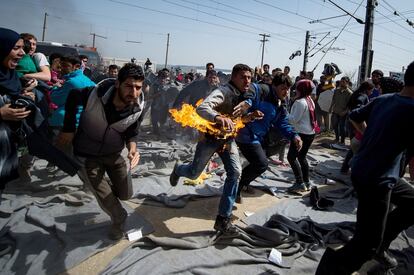 Un hombre corre desesperado después de haberse prendido fuego en el campamento griego de Idomeni durante una protesta del grupo de migrantes que mantiene ocupadas las vías del tren para exigir la apertura de las fronteras, el 22 de marzo de 2016.