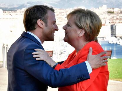El presidente francés Emmanuel Macron (i) abraza a la canciller alemana, Angela Merkel, este viernes en Marsella