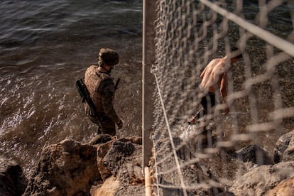 Un soldado del ejército junto a un inmigrante a su llegada a la playa de El Tarajal en Ceuta, este miércoles. La frontera de Ceuta entre Marruecos y España ha amanecido con solo unas decenas de inmigrantes que intentan llegar a nado, una situación que difiere de la registrada hace dos días, cuando llegaron 8.000 personas,.