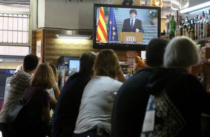 Varias personas escuchan el discurso del ex presidente Carles Puigdemont en un bar del centro de Barcelona.