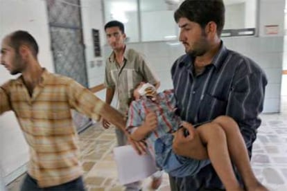 Un hombre lleva en brazos a un niño herido por la explosión de un coche bomba ayer en Bagdad.