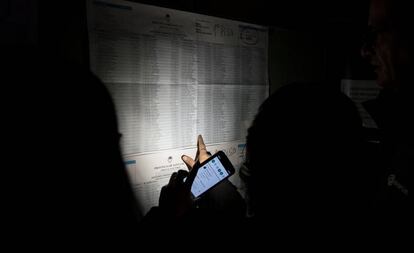 Una persona ilumina con su móvil el listado de electores asignados a una mesa de Rosario, en Santa Fe, en medio del apagón que afectó a Argentina el domingo.