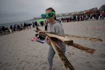 Una joven transporta madera en la playa de Riazor, A Coruña, de cara a la celebración de la noche de San Juan, donde miles de personas volverán festejar la fiesta más multitudinaria del año tras el parón de la pandemia. 
