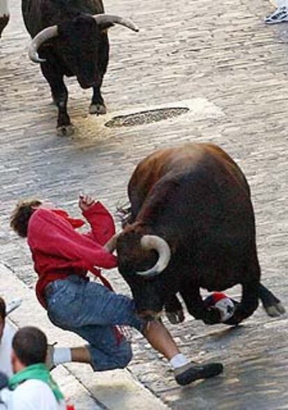 Un toro voltea a un joven en el encierro de ayer.