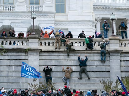 Rioting supporters of President Donald Trump climb the west wall of the the US Capitol in Washington.