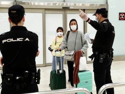 Dos viajeros y dos policías, en el aeropuerto de Barajas (Madrid).