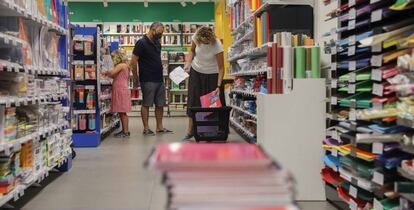 Una pareja acompañados por una niña realizan una compra de material escolar en una papelería de Valéncia.