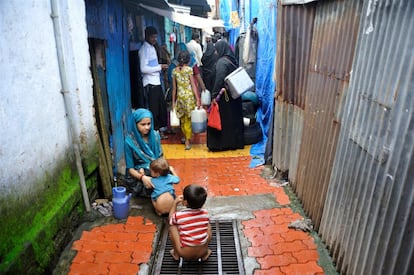 Una madre ayuda a sus hijos a hacer sus necesidades en medio de la calle, ya que no tienen baño en su casa de Bombay (India).