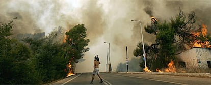 Un cámara de televisión camina junto a las llamas cerca de Zaharo, en el Peloponeso