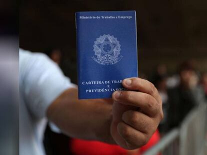 Homem em busca de trabalho mostra carteira de trabalho em 20 de março.