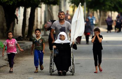 Una anciana sujeta una sábana blanca mientras es ayudada a salir del barrio gazatí de Shiyahiya, el 20 de julio de 2014.
