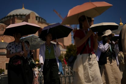 Turistas utilizan parasoles para protegerse del calor en la mezquita de Hagia Sofia, en Estambul, Turquía.