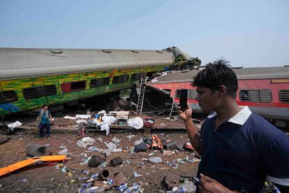 Un hombre hace fotos con su móvil junto a los restos del vagón accidentado. 