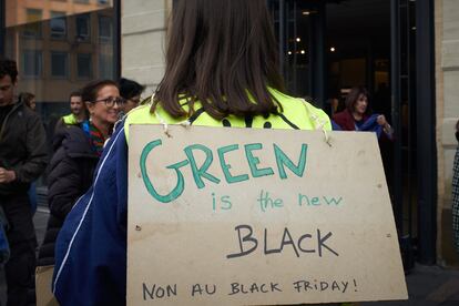 Una manifestante con un cartel con el lema: "El verde es el nuevo negro. No al Black Friday".