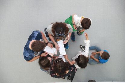 Varias personas comprueban sus papeletas antes de proceder al voto en el colegio público Federico García Lorca de Boadilla del Monte, Madrid.