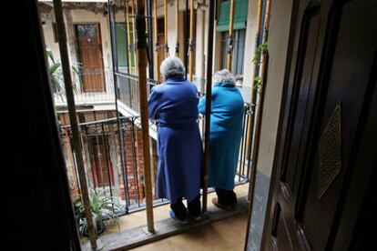 Dos vecinos en una corrala en el barrio de Embajadores, asomadas a un balcón de la vivienda.