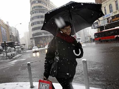 Una mujer camina con precaución por la Gran Vía bajo la intensa nevada.