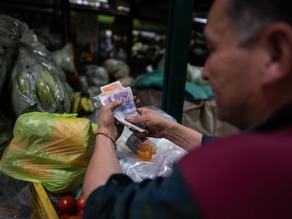 Un vendedor cuenta su dinero en la plaza de Paloquemao, en Bogotá.