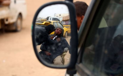 A picture taken through the reflection of a car's side mirror on April 29, 2017 at a temporary camp in the village of Ain Issa shows a displaced Syrian, who fled the countryside surrounding the Islamic State (IS) group stronghold of Raqa, having his beard shaved. / AFP PHOTO / DELIL SOULEIMAN