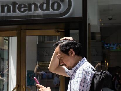 Un home juga al Pokémon Go al costat d'una botiga de Nintendo a Nova York