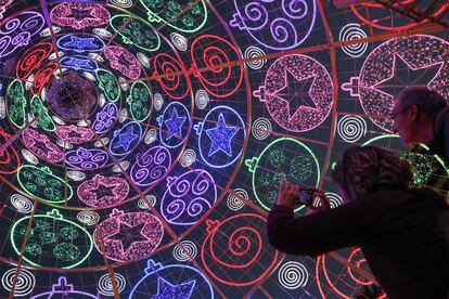 Dos personas fotografían el interior del árbol de Navidad que ilumina el centro de Valencia.