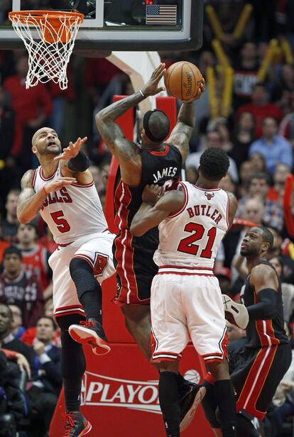 LeBron, de los Heat, lanza empujado por Butler y marcado por Boozer, de los Bulls.