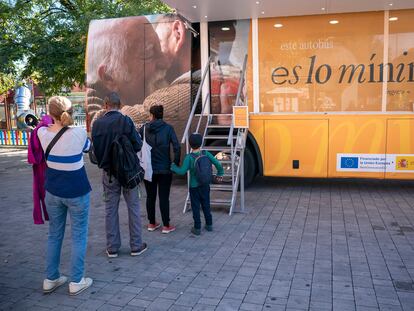 Gente haciendo cola para entrar en un autobús que informa sobre el Ingreso Mínimo Vital (IMV) en Parla (Madrid).