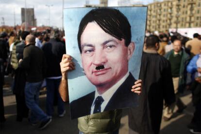 Un manifestante sostiene una foto del presidente Hosni Mubarak caracterizado como Hitler.