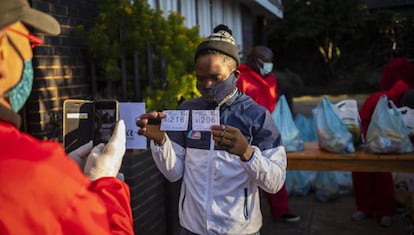 Un voluntario toma una fotografía de una persona que recibe alimentos durante el programa semanal de alimentos en la Iglesia Bautista Heritage en Melville, Johanesburgo, Sudáfrica.