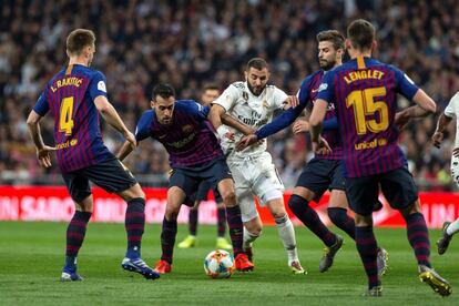 El delantero francés del Real Madrid Karim Benzema lucha con Sergio Busquets, del FC Barcelona, por hacerse con la posesión del balón.