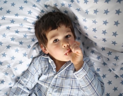Un niño se chupa un dedo mientras observa con atención.