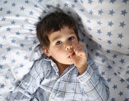 Un niño se chupa un dedo mientras observa con atención. 