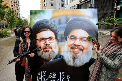 Una mujer sostiene un fusil mientras se hace una foto con los carteles de los líderes de Hezbolá asesinados por Israel, este miércoles en Beirut. 